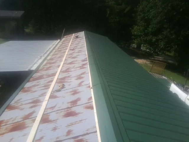 Old rusted panels beside newly installed green metal roofing — Wind Damage Roof Repair by Roofing Brothers in Croton