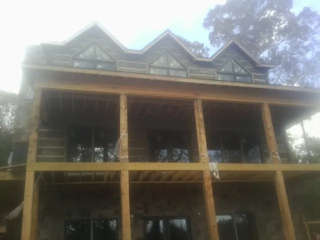 Dormers and porch framing on a large log home under construction — Roof Coating work by our crew in Croton