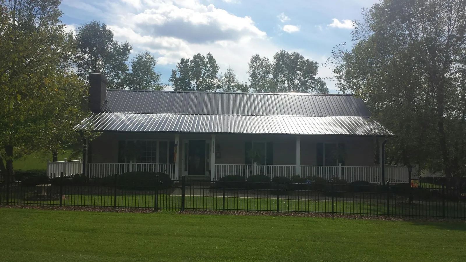Gray metal roof on a brick ranch with a full width front porch — Gutter Guard Installation work by our crew in Croton
