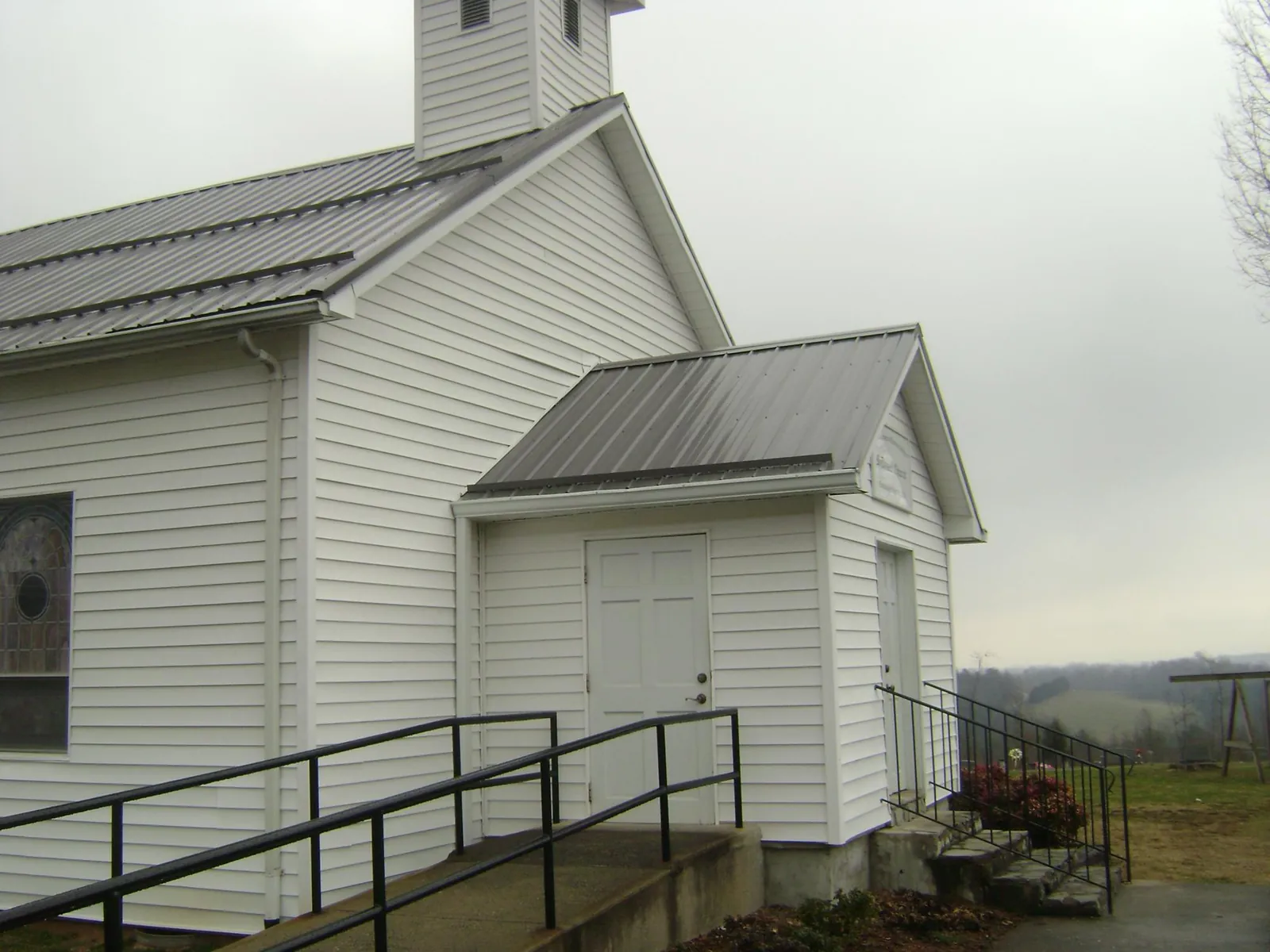 Gray metal roof on a white clapboard church with a steeple in Croton