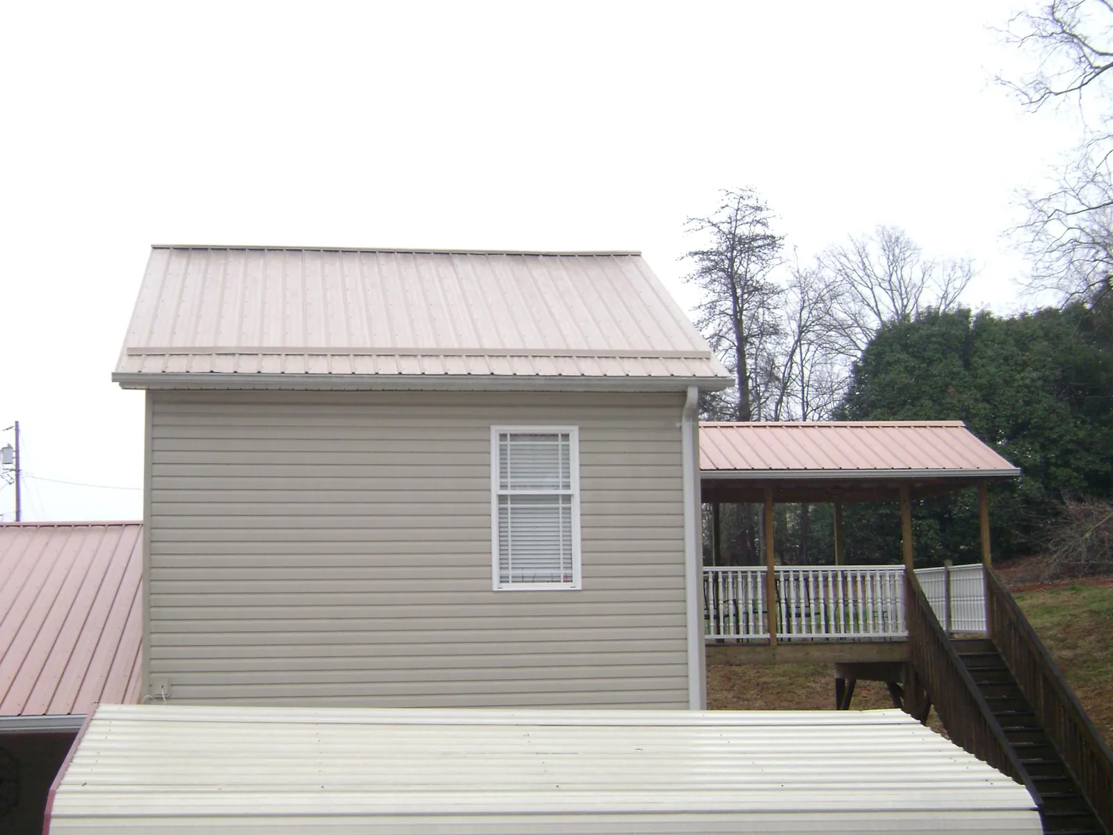 Tan metal roofs on a two story addition and attached porch, from a Roof Replacement job in Croton