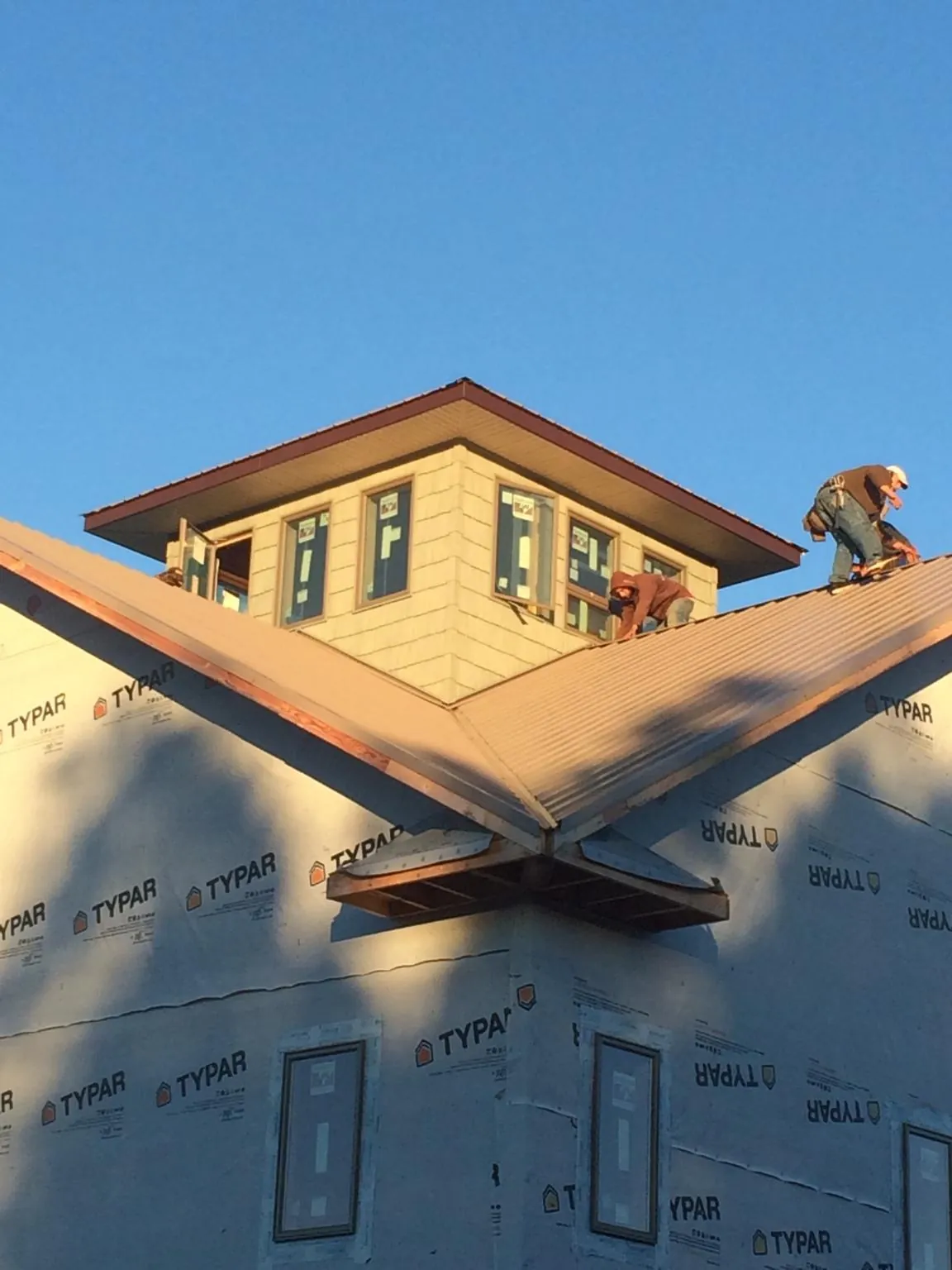 Roofers working around a rooftop cupola on a new metal roof at sunset — Roof Waterproofing in Croton by Roofing Brothers